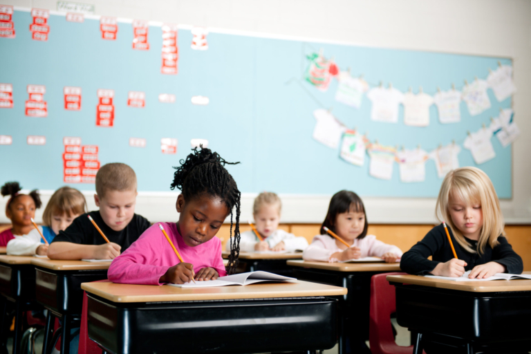 Students use pencils to write in their phonics workbooks