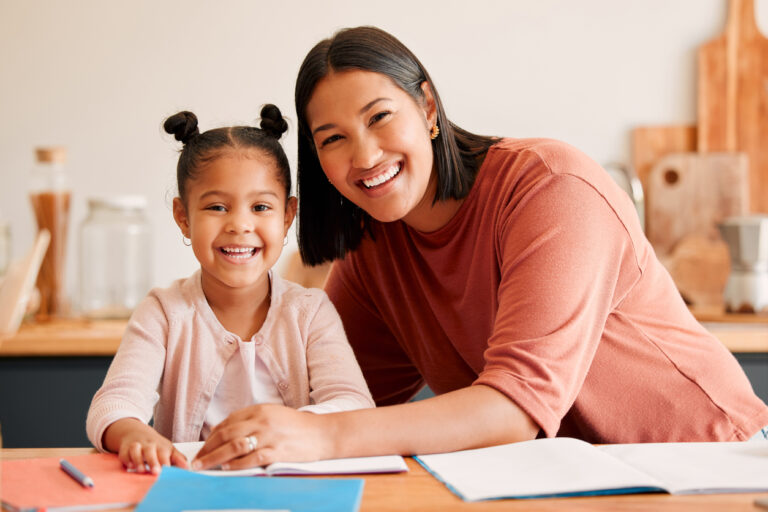 Mother helping, teaching and educating daughter with homework at home. Portrait of happy, loving and smiling mom and little girl busy with educaional lesson, tutoring or assistance at home together